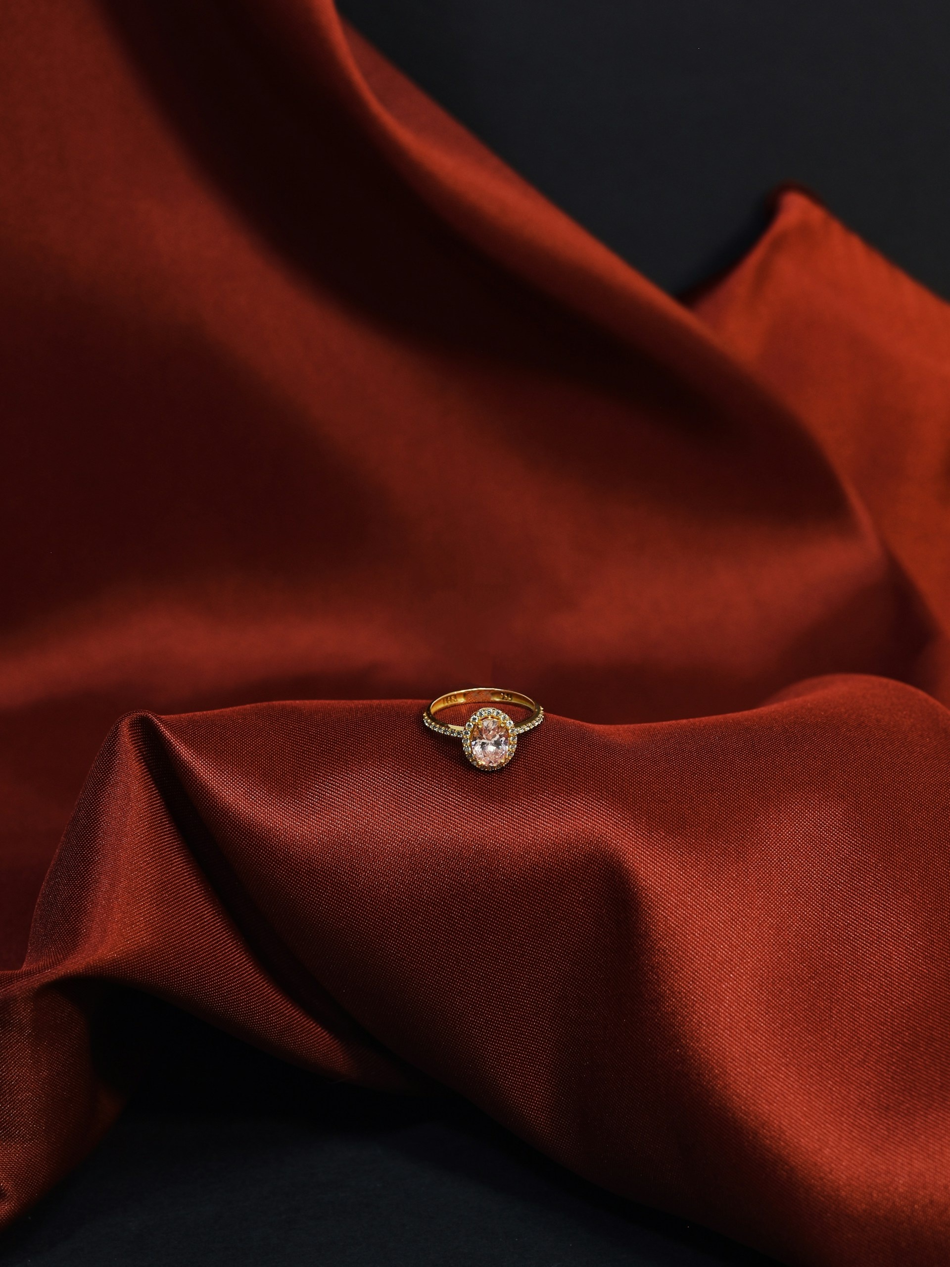 Gold ring with large brilliant diamond on satin, warm amber reflections