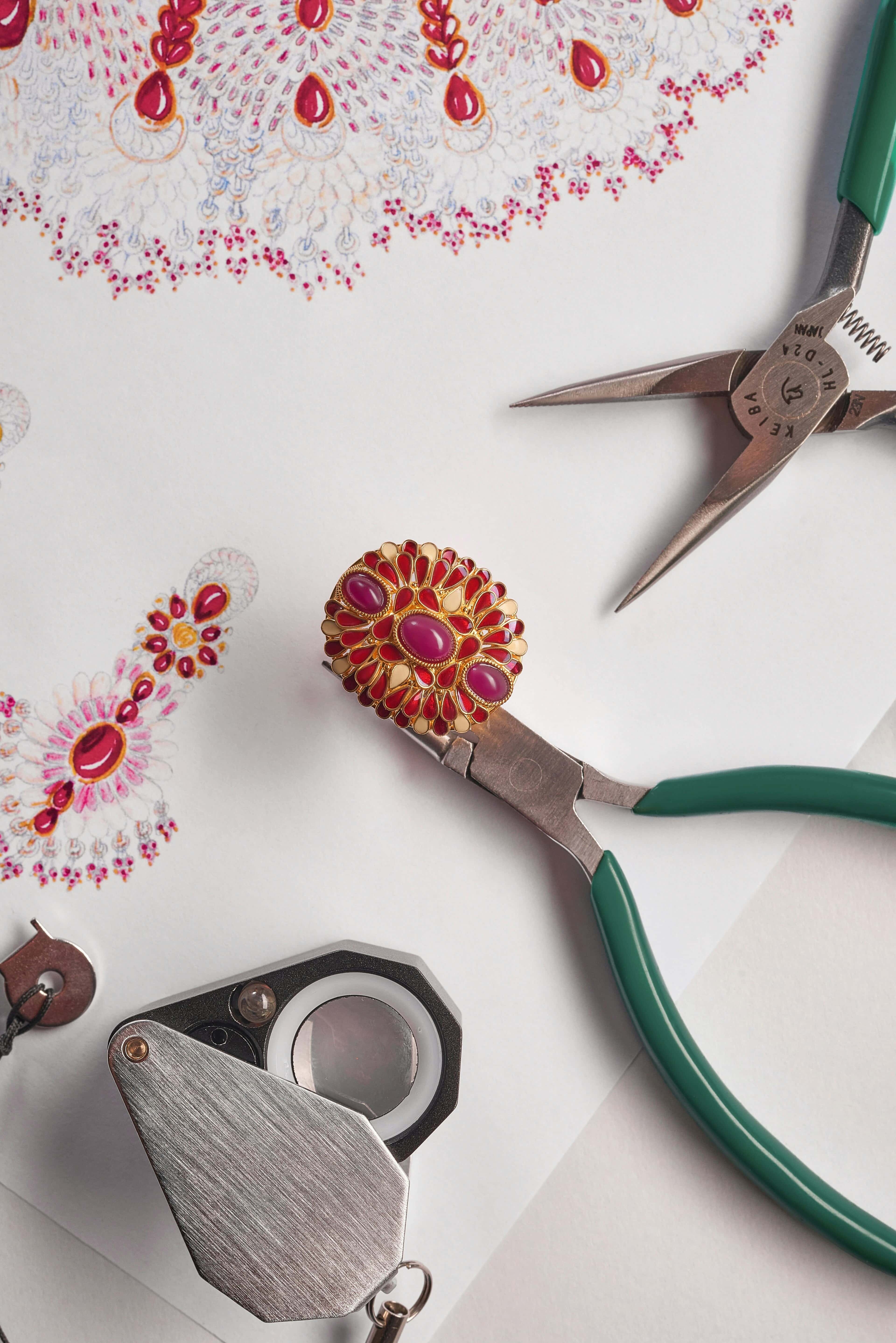 Jewelry design sketches with tools, gemstones, and gold rings on a dark surface
