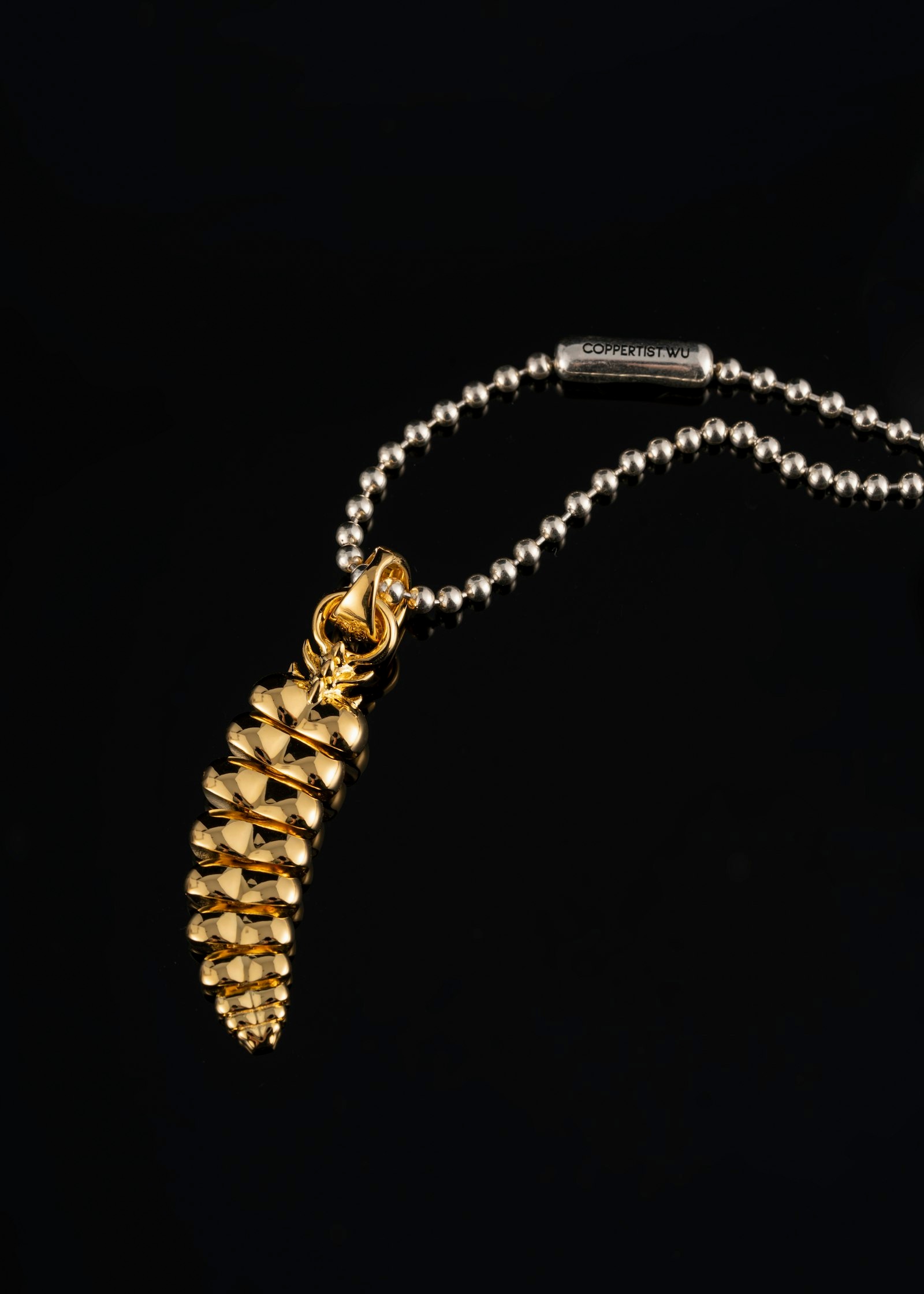 Gold pendant necklace with backlit rim light on dark background